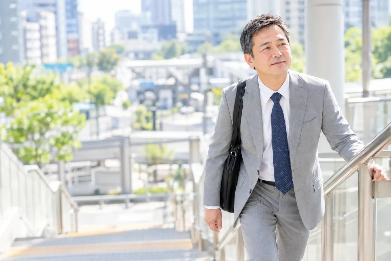 朝、駅の階段を上るスーツ姿の50代の男性